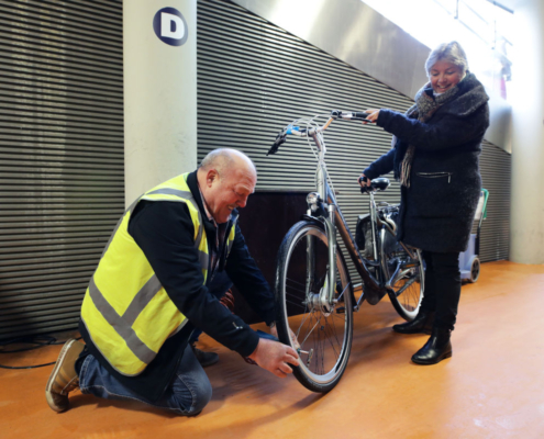 Een DZB collega die bij de fietsenstalling werkt helpt een klant